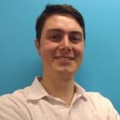 Smiling person in a white shirt against a blue background.