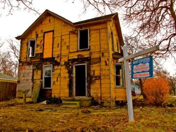 Old, abandoned two-story house with boarded windows and a