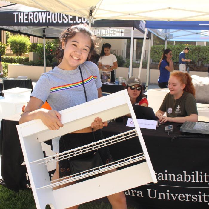 A student smiling holding a shelf at the 2019 Welcome Weekend Bronco Surplus booth