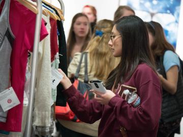 Group of people looking at clothing on a rack.