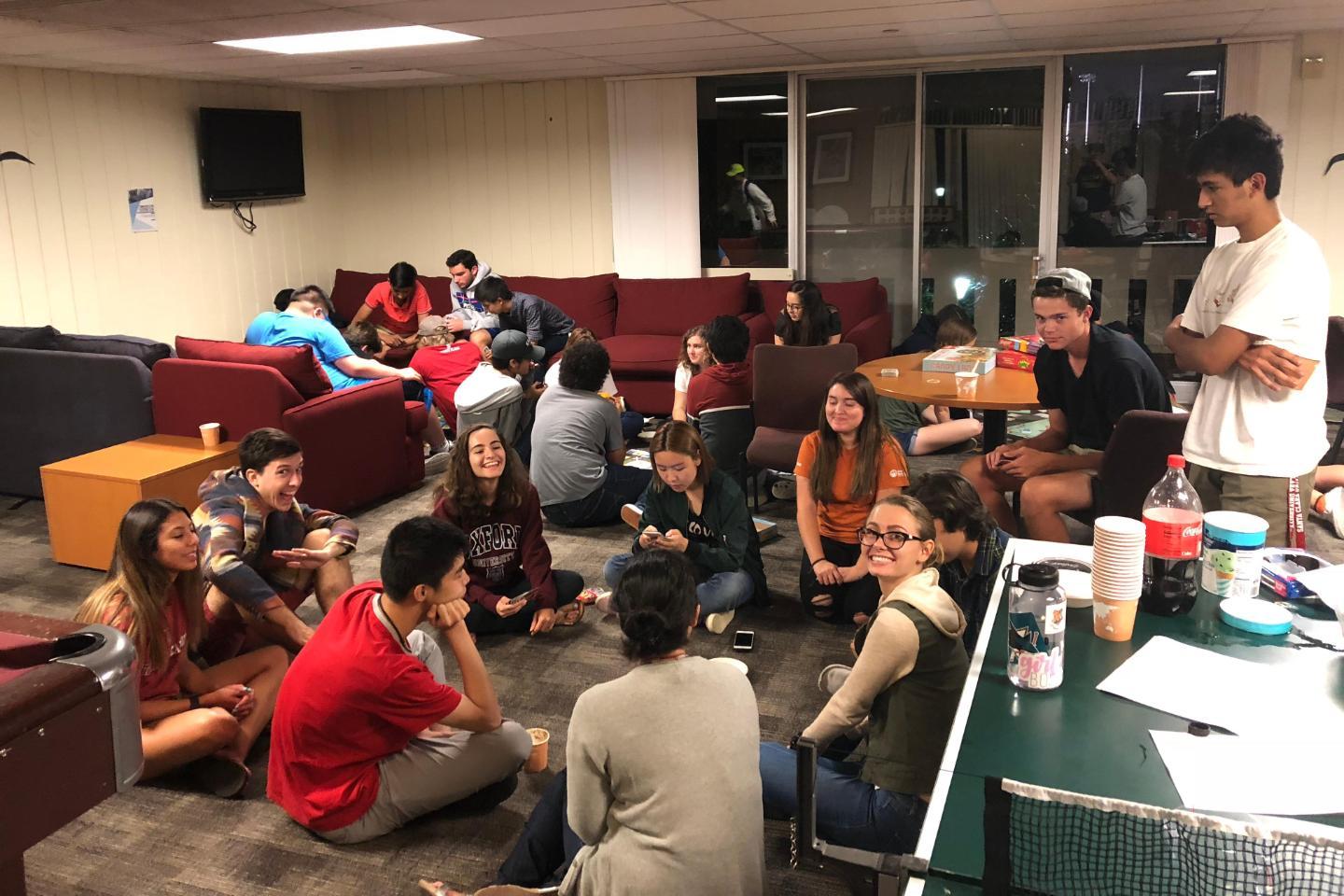 A crowded common room with groups of students chatting and socializing