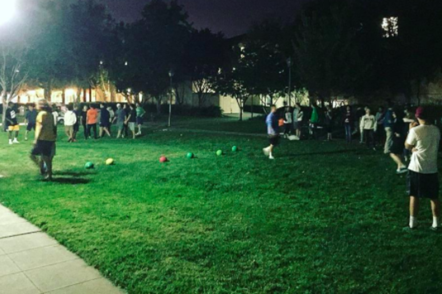 Teams of residents playing dodgeball on a field at night