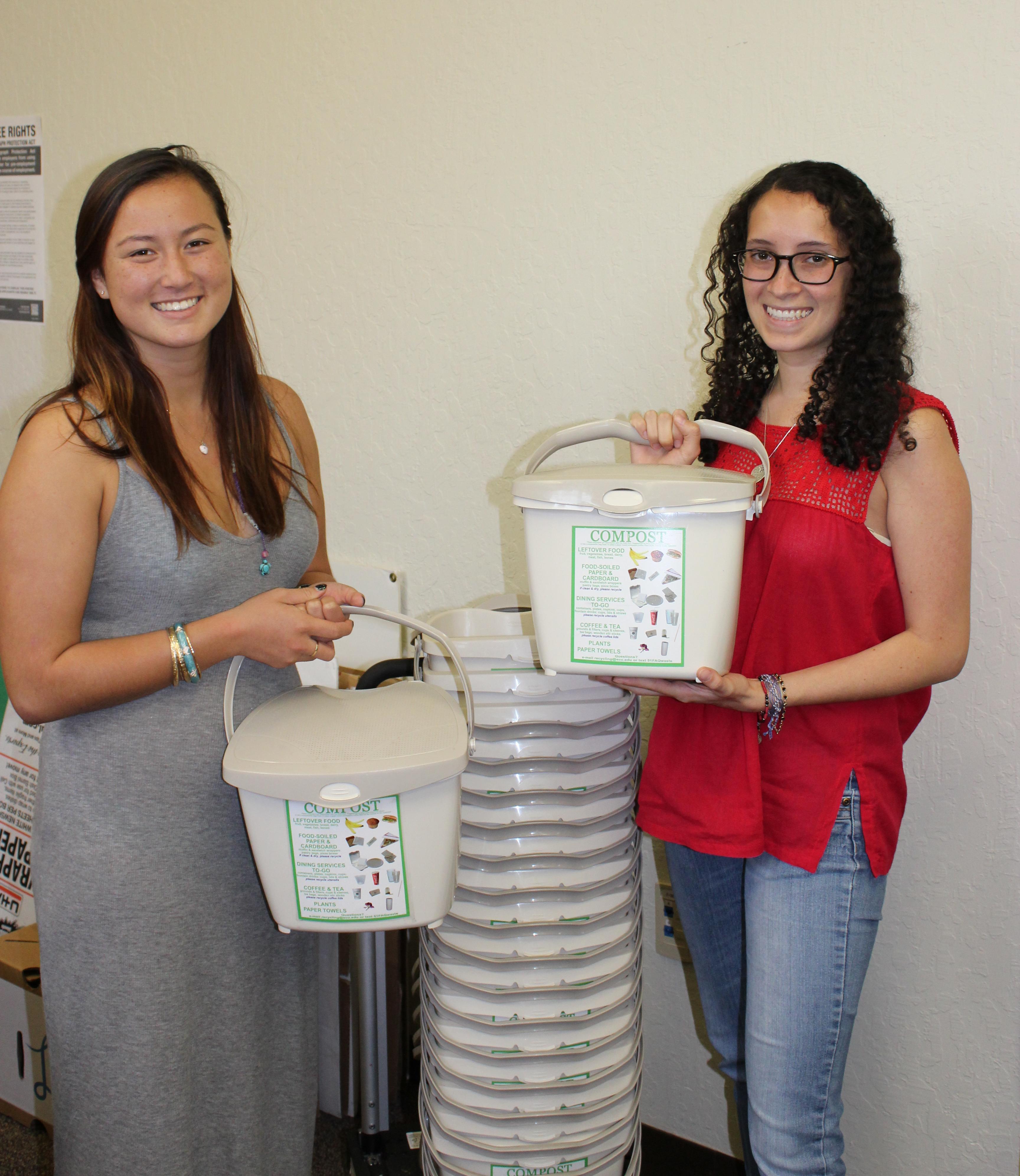 Two women holding compost bins in a room titled 