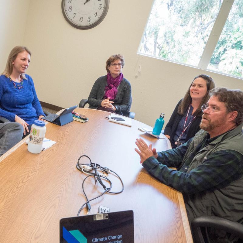 A group of faculty and staff meeting in a conference room, photo by Charles Barry