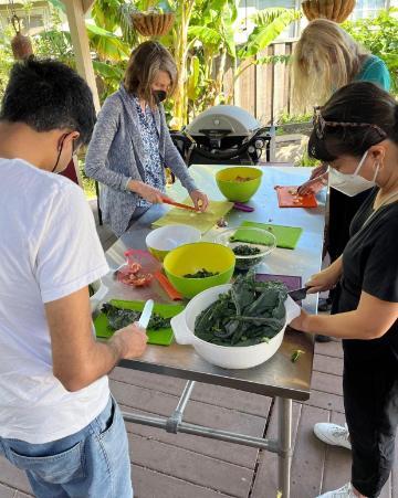 Faculty and students stand outside chopping veggies