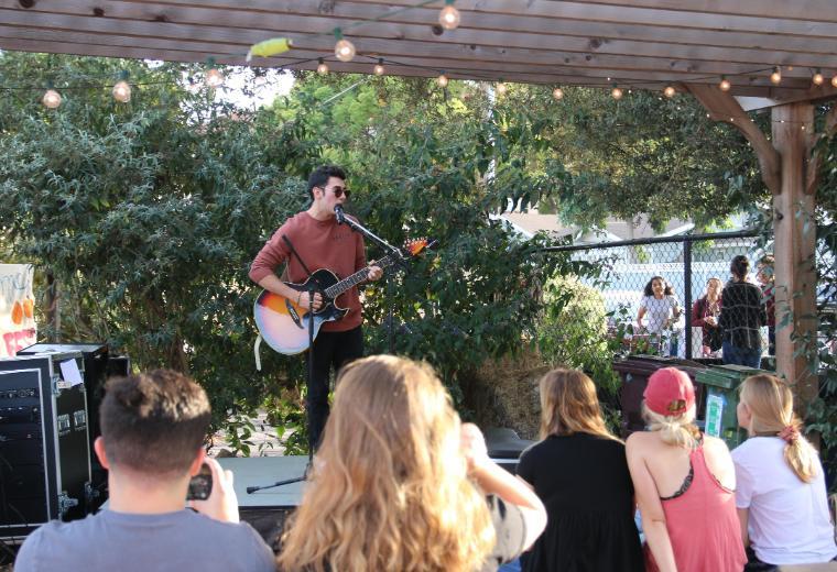 A student singing and playing the guitar at the Forge Garden in front of an audience