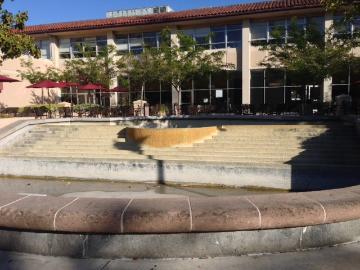 Empty fountain in front of a building on a sunny day.