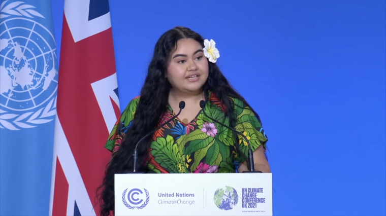Pacific climate activist Brianna Fruean speaks on stage behind a podium at the UN Climate Change Conference