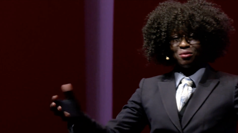Dr. Atyia Martin speaks on stage in front of a dark purple background