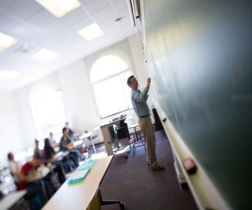 A professor teaching a class in a well-lit classroom.