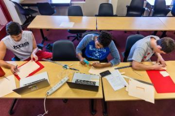 Students working at a table with art supplies.