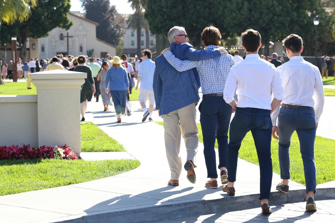 A large group of people with men in the foreground are walking towards the Mission Church. image link to story