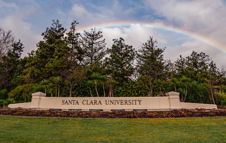 A rainbow appears above the Santa Clara University entrance sign