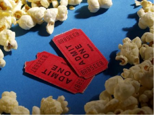 Red Admit One tickets surrounded by popcorn on a blue surface.