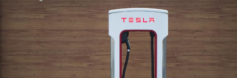 Close up of a Tesla supercharger in front of a wood wall