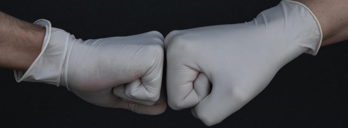 Photo of two fists in rubber gloves pushing eachother.