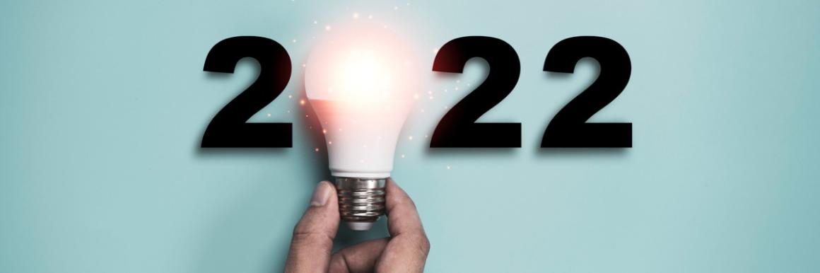 Man's hand holding lightbulb in front of year 2022.