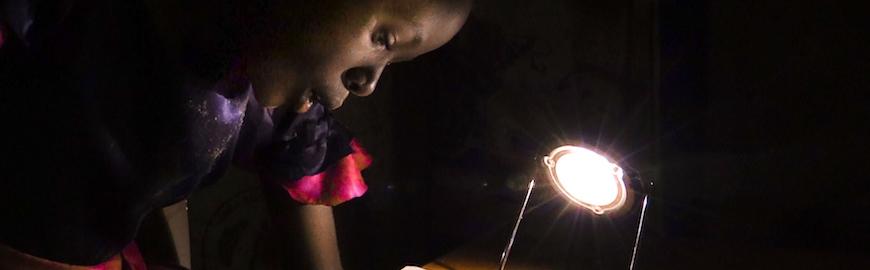 African girl reading in the dark with the assistance of a lamp