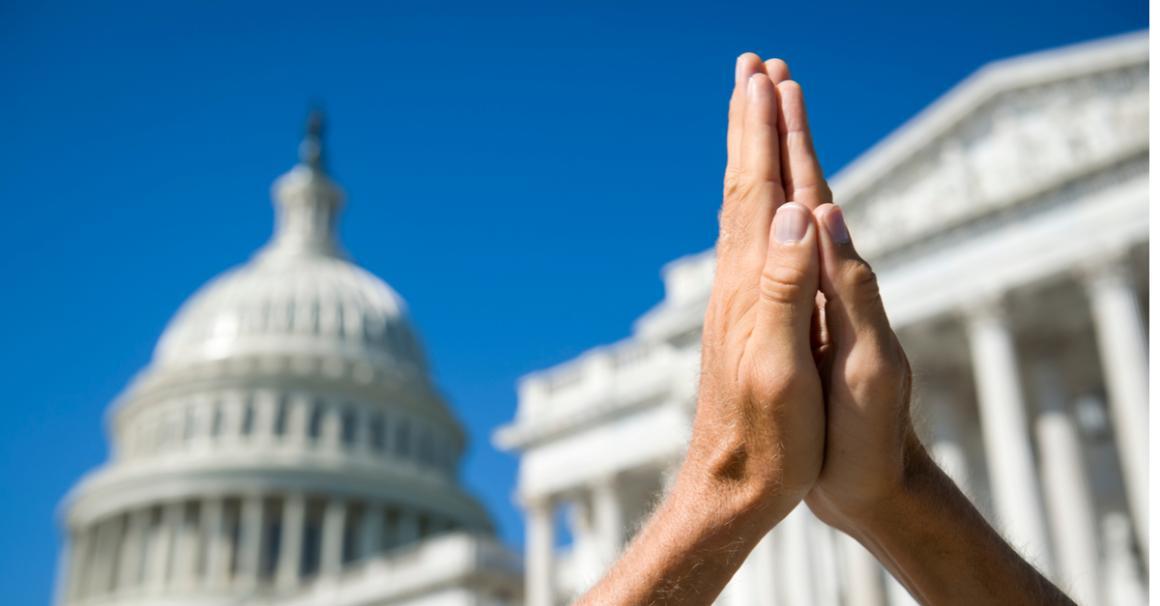 photo of raised hands praying before u.s. capitol 