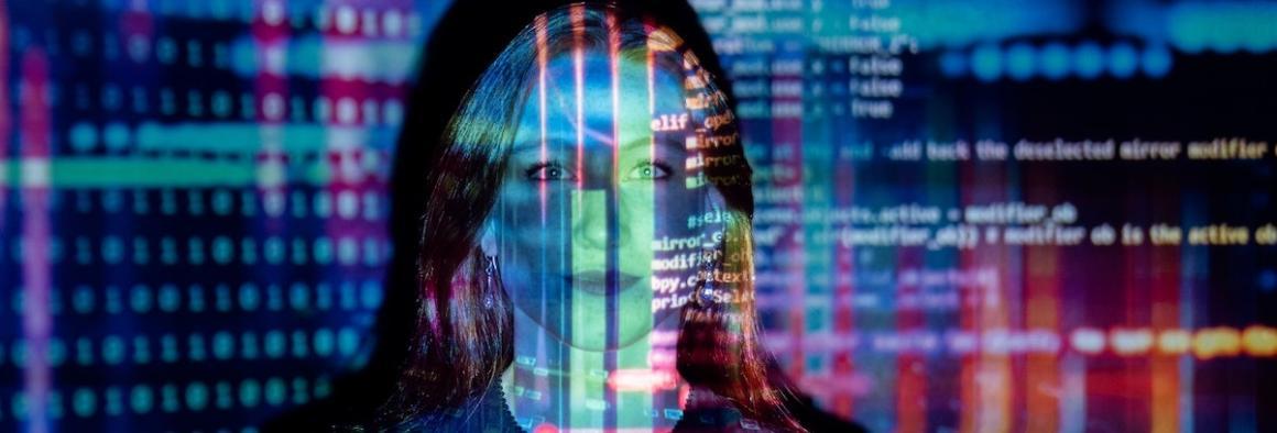 Photo of a woman's face accented by a light projection of colorful software coding.