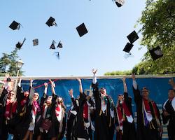 SCU graduates throwing their caps in the air