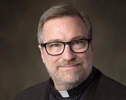Head shot of a bearded priest in glasses.