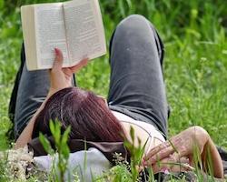 Woman laying on grass and reading a book 