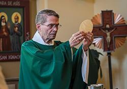 Fr. Rewak holding up the Host at Mass.