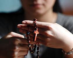 Close up of young woman holding a rosary.