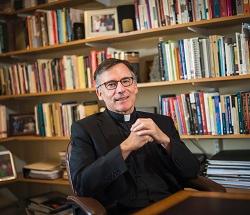 Portrait of Fr. Kevin O'Brien in front of a book case.