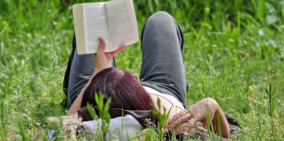 Person laying in grass reading