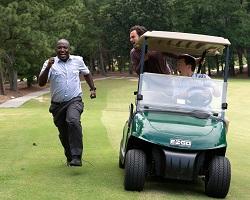 Man running next to a golf cart.