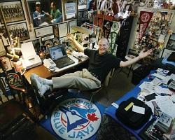 Man sitting in an office filled with sports memorabilia..