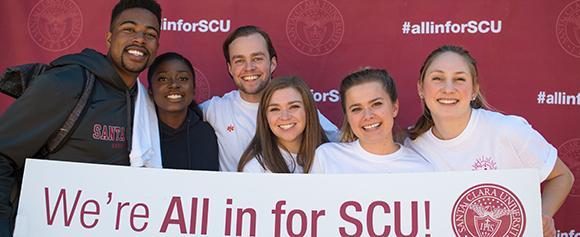 Students standing behind All in for SCU sign.