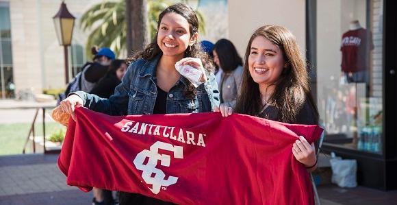 Two female students holding a Santa Clara banner.