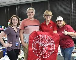 A group of four individuals standing behind a red SCU banner.