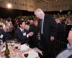 Two men shaking hands at an awards dinner.