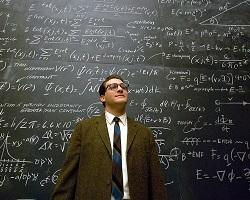 Potrait of a man standing in front of a chalkboard filled with formulas.