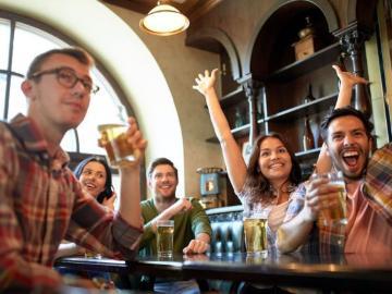 Group of people at a bar cheering at a trivia game