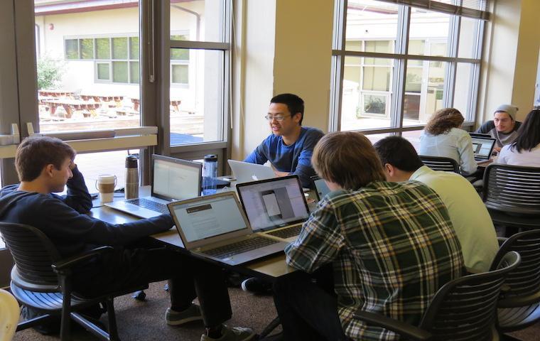 People working on laptops together in a room during a hackathon. image link to story
