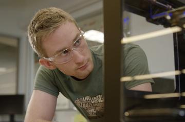 A student with protective glasses working on a product 