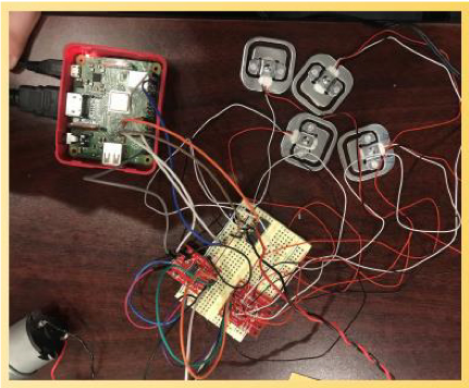 Arduino with black, red, and while wires leading to load cells for testing the readings during prototyping on a brown table. 