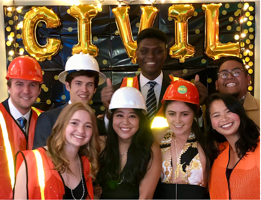 Four male and four female CESE students pose in front of a civil engineering sign during a formal department party.  Two men and two women wear orange or white hard hats and/or orange safety vests. Students are of White, Black, Asian, Native American and Hispanic descent. 