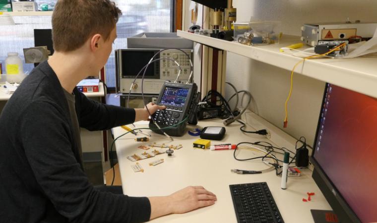 Graduate student working on Electrical Engineering equipment in lab.