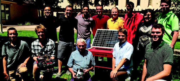 Mike Wagner (center, in yellow shirt) gets a demo of the solar-powered car and charging station from the Latimer Energy Scholars. image link to story