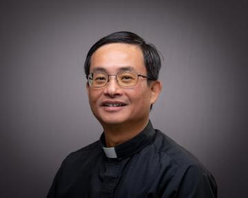 Father Tran headshot with grey background.