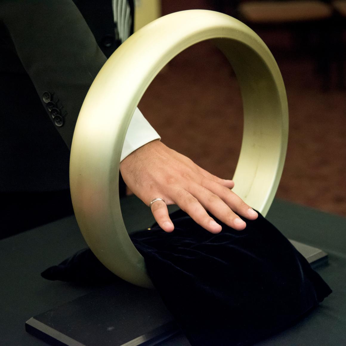 A hand passing through a large ring during a ceremony.