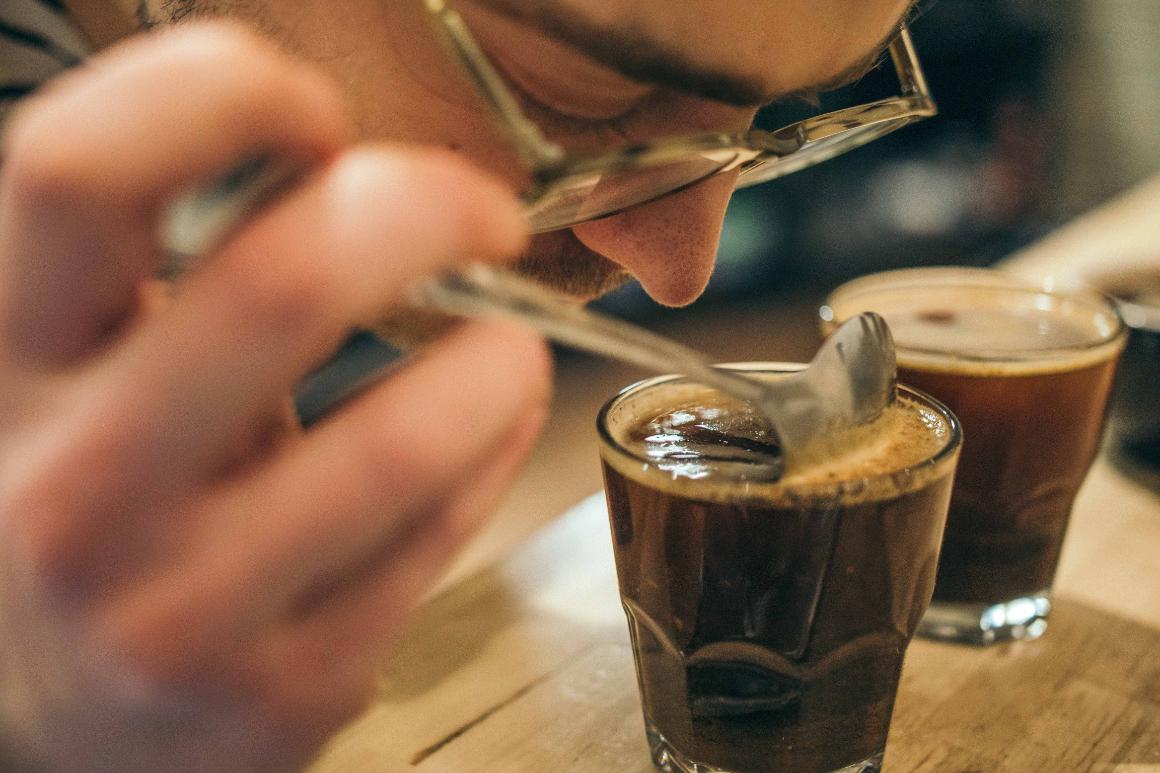 A man puts his nose over a glass of coffee to determine its aroma. image link to story