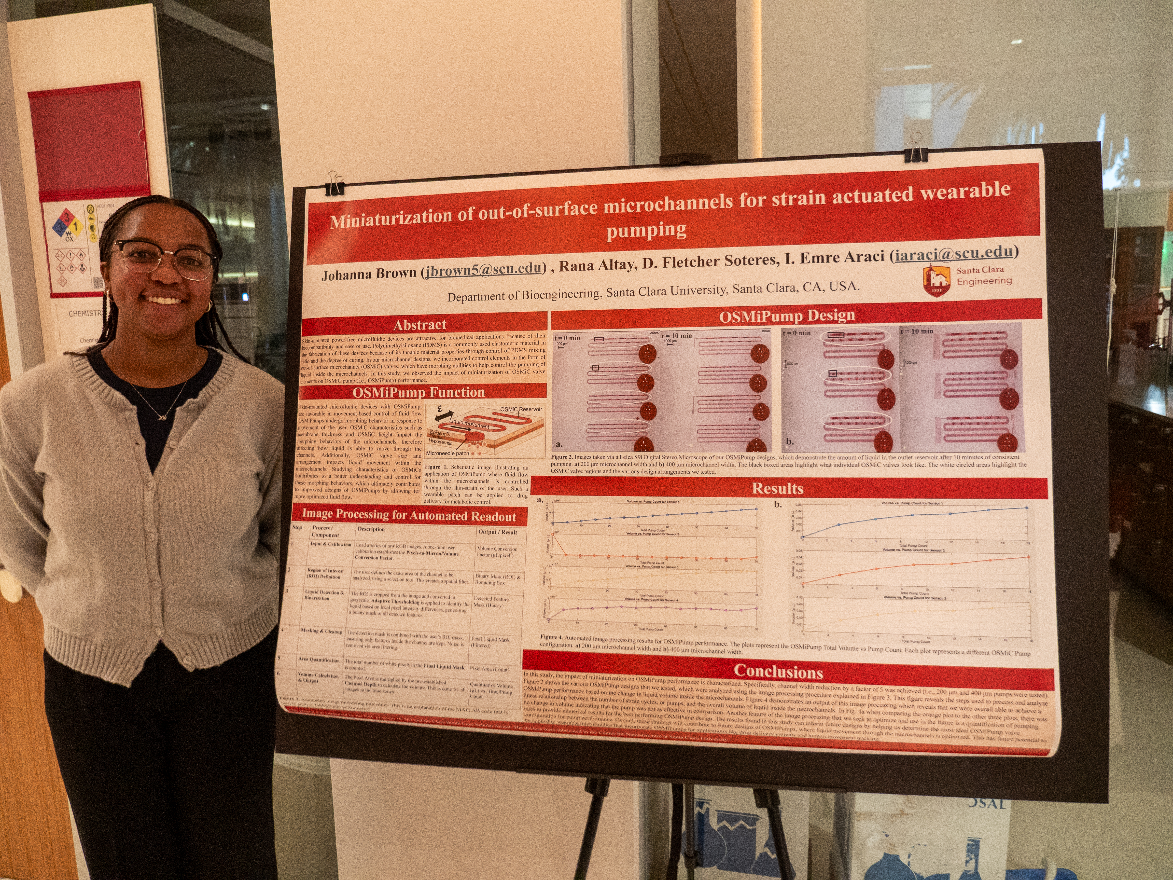 Female students wearing a cardigan standing to the left of her Research Poster