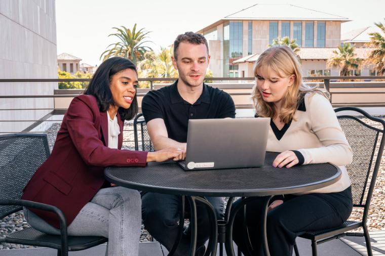 Law school students working together on a laptop outside.